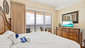 Une chambre d’hôtel avec un grand lit, une télévision, une commode et un balcon donnant sur l’océan.