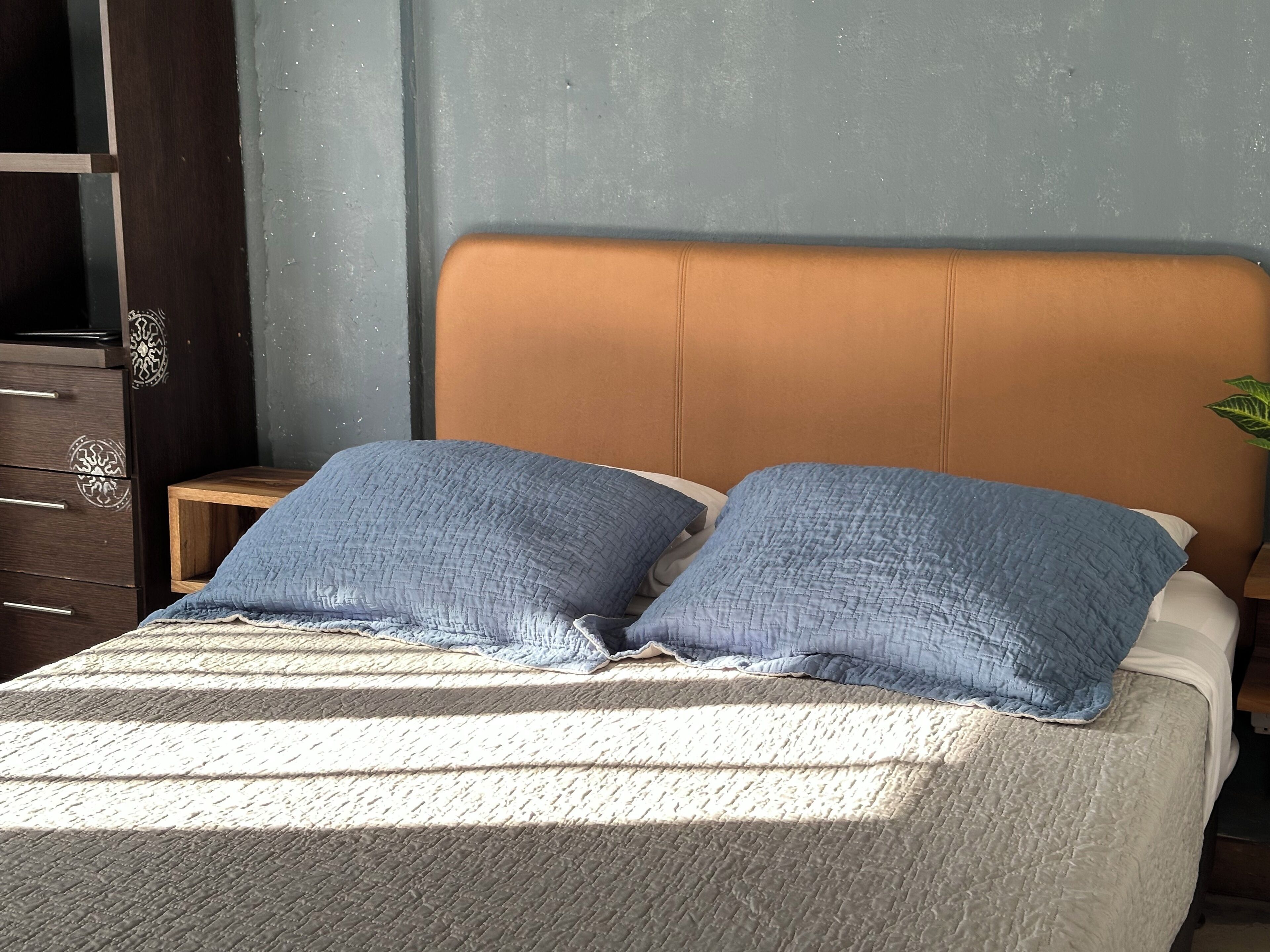 Un lit avec une couverture à rayures, deux oreillers et une table de chevet en bois.