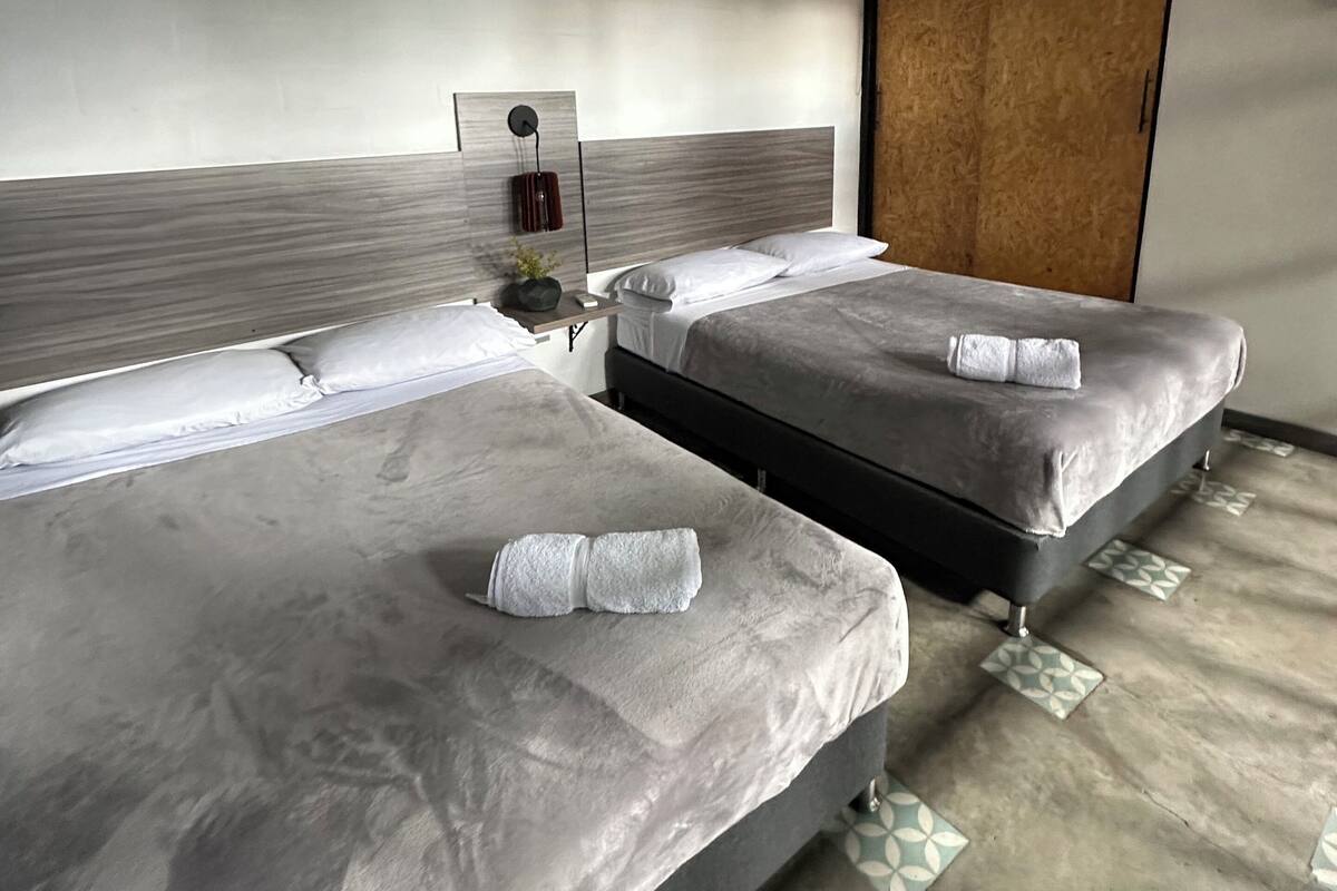 Une chambre d’hôtel avec deux lits, une tête de lit en bois et une grande fenêtre.