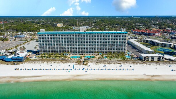 A large hotel with multiple floors, a pool, and a beach area with umbrellas. - The Summit 1032 (Panama City Beach)