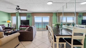 A spacious living area with a dining table, sofas, a TV, and a ceiling fan. - The Summit 1512 (Panama City Beach)