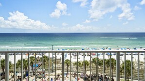 Blick auf einen Strand mit klarem Himmel, Palmen und Strandsonnenschirmen.