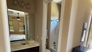 A bathroom with a double vanity, a toilet, a shower, and a ceiling fan.