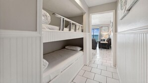 A narrow hallway with bunk beds, a dining area with a table and chairs, and a view of the outdoors. - The Summit 725 (Panama City Beach)
