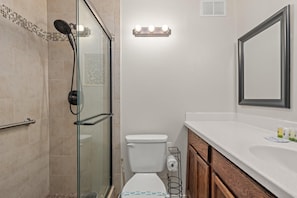 A bathroom with a glass shower enclosure, a toilet, a vanity with a mirror, and a sink. - Top Of The Gulf 111 (Panama City Beach)