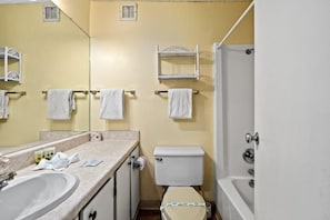 A bathroom with a sink, toilet, and bathtub. There are towels hanging on a rack and a mirror above the sink.