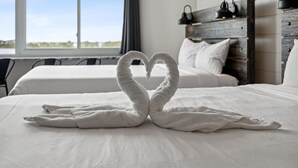 Een hotelkamer met een bed, versierd met handdoeken in de vorm van een hart, een houten hoofdeinde en uitzicht op de omgeving.