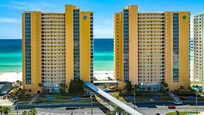 Um hotel com vários andares, vista para a praia e estacionamento.