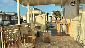 Una veranda coperta con arredi in legno, un tavolo da pranzo e vista sulle case vicine.