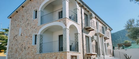 Un edificio de dos pisos de piedra con balcones, fachada de piedra y un camino empedrado que conduce a una puerta.