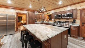 Una cucina moderna con rivestimenti in legno, elettrodomestici in acciaio inossidabile e un'isola in marmo.