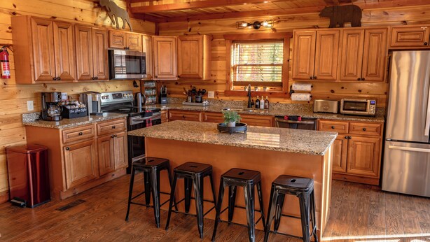 Cocina estilo cabaña de madera con encimeras de granito, electrodomésticos de acero inoxidable y armarios de madera.