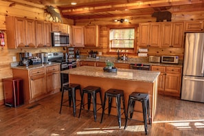 A wooden cabin-style kitchen with granite countertops, stainless steel appliances, and wooden cabinets.