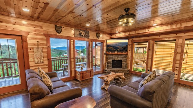 Un interior de madera con sofás, una chimenea y ventanas amplias.