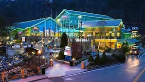 Un hotel con fachada de vidrio moderna, un área exterior cubierta y un estacionamiento.