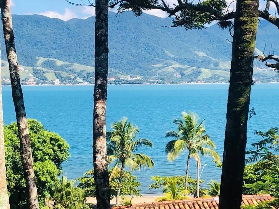 Un paisaje costero con vista al mar, palmeras y colinas al fondo.