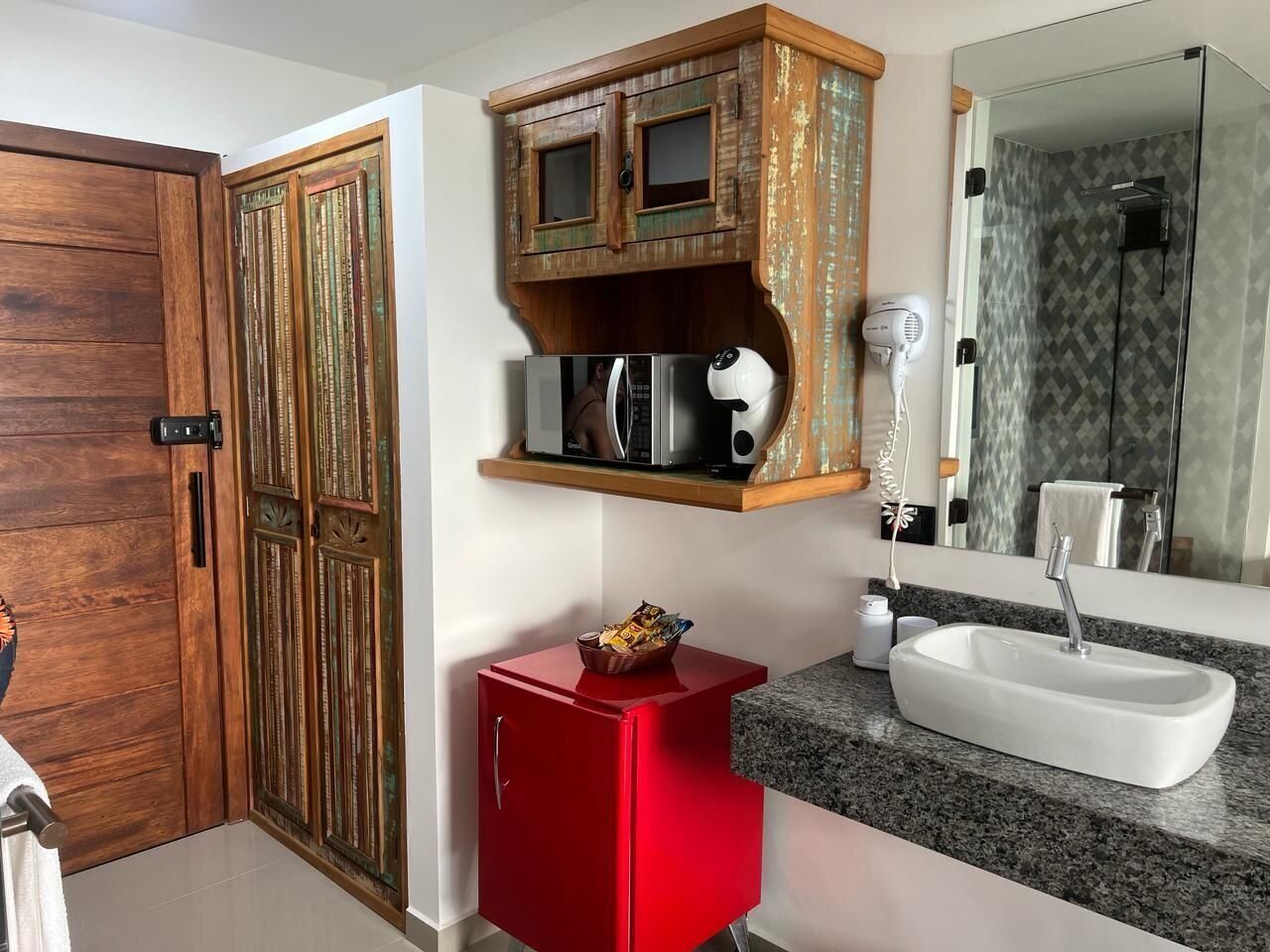 Une salle de bain avec une armoire en bois, un meuble rouge, un lavabo blanc et un miroir.