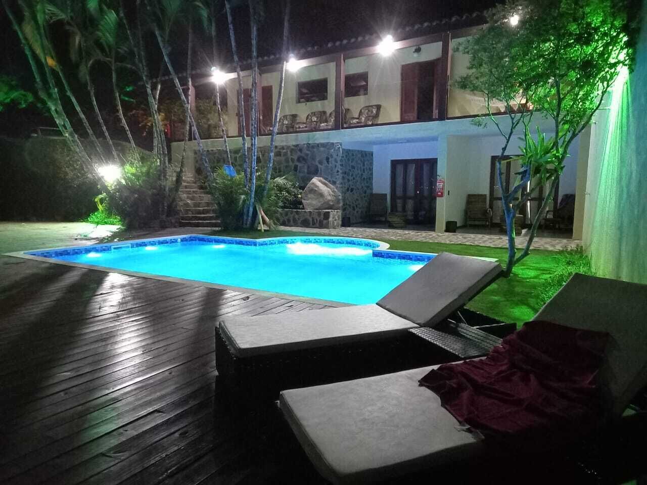 A swimming pool with lounge chairs and a stone wall.