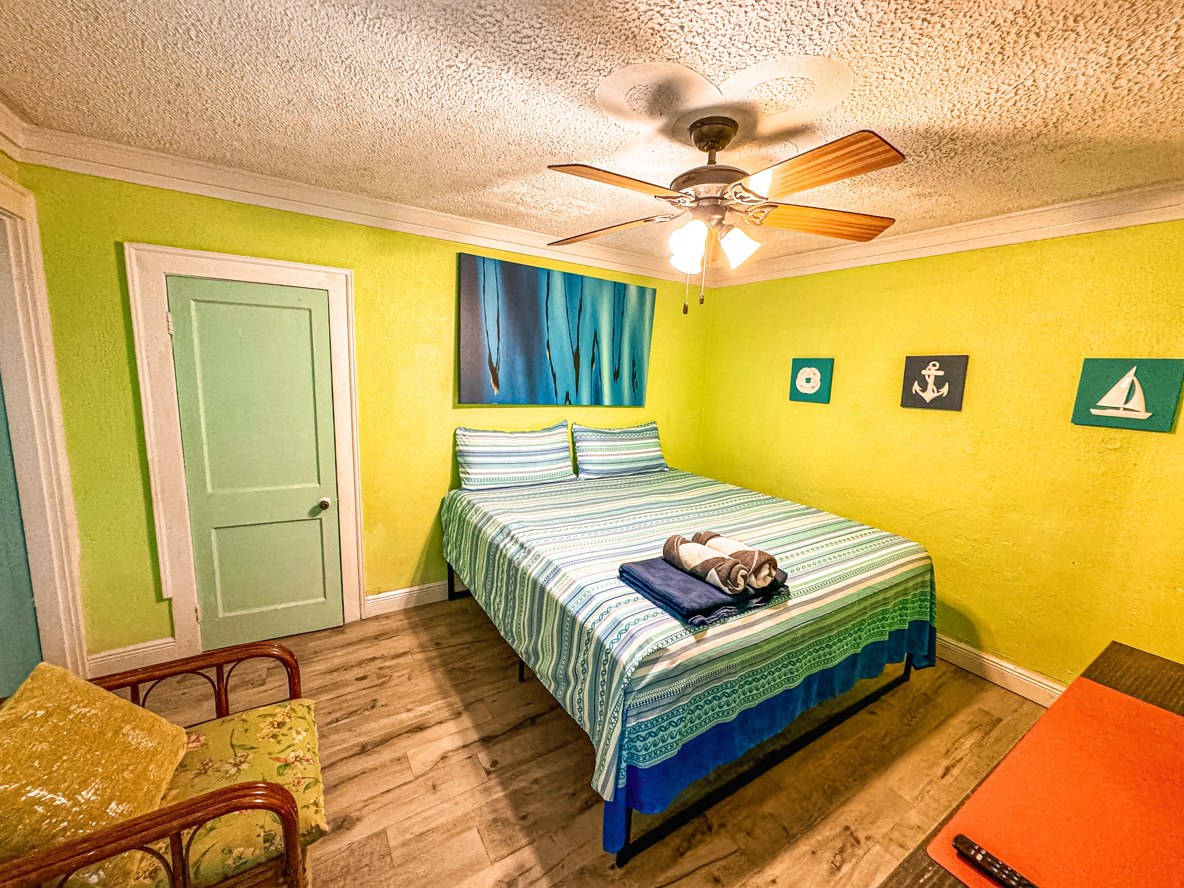 A bedroom with a bed, a ceiling fan, and a door.