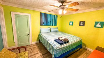 A bedroom with a bed, a ceiling fan, and a door.