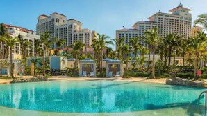 A hotel with a large pool surrounded by palm trees and beach umbrellas. - COMPLimentary Car! Casa Azul! (Nassau)