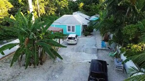 A house with a blue roof, surrounded by lush greenery and a gravel driveway. - COMPLimentary Car! Casa Azul! (Nassau)