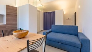 A modern living room with a wooden dining table, blue sofa, and a large mirror. - Loft Piazza Marina (Palermo)