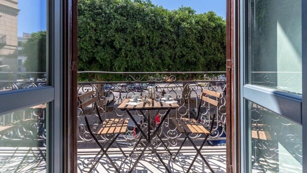 A balcony with metal railings and wooden tables and chairs. - Loft Piazza Marina (Palermo)
