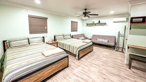 Une chambre avec deux lits, un ventilateur de plafond et un banc.