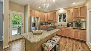 A modern kitchen with wooden cabinets, stainless steel appliances, and a central island with seating.