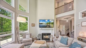 A spacious living room with a fireplace, large windows, and a view of a lake.