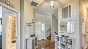 A hallway with a wooden floor, a white door, a staircase, and a decorative mirror.