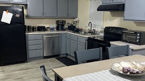 A modern kitchen with grey cabinets, a black refrigerator, a coffee maker, and a toaster. -  Looking for relaxation and comfort? Look no further with all its amenities.  (Indianapolis)