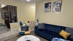A living room with a blue sofa, a round coffee table, and a ceiling fan. -  Looking for relaxation and comfort? Look no further with all its amenities.  (Indianapolis)