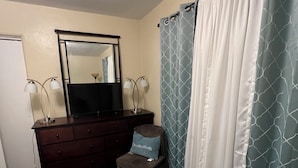 A bedroom with a bed, a dresser, a chair, a mirror, and a shower curtain. -  Looking for relaxation and comfort? Look no further with all its amenities.  (Indianapolis)
