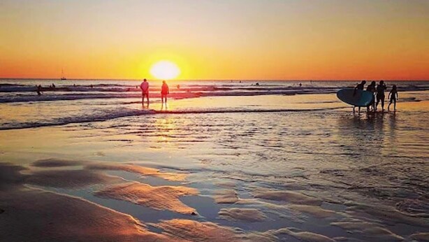 A beach scene with people walking and a sunset in the background. - Beautiful 2-bed Apartment in Rhosneigr (Rhosneigr)