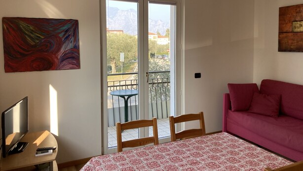 A room with a bed, a couch, a TV, and a painting. - Bikeapt Two-bedroom apartment 3 with lake view and private parking a stone's throw from downtown (Malcesine)