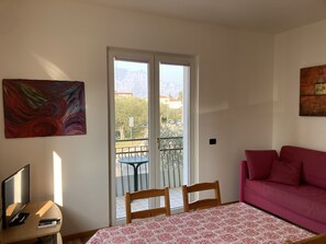 A room with a bed, a couch, a TV, and a painting. - Bikeapt Two-Bedroom Apartment 3 with a lake view and private parking, just a stone's throw from downtown (Malcesine)