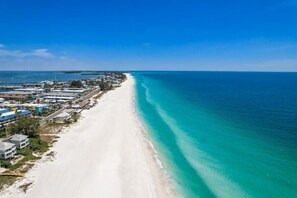 Blick auf die Küste mit einem Sandstrand und klarem türkisblauem Wasser.