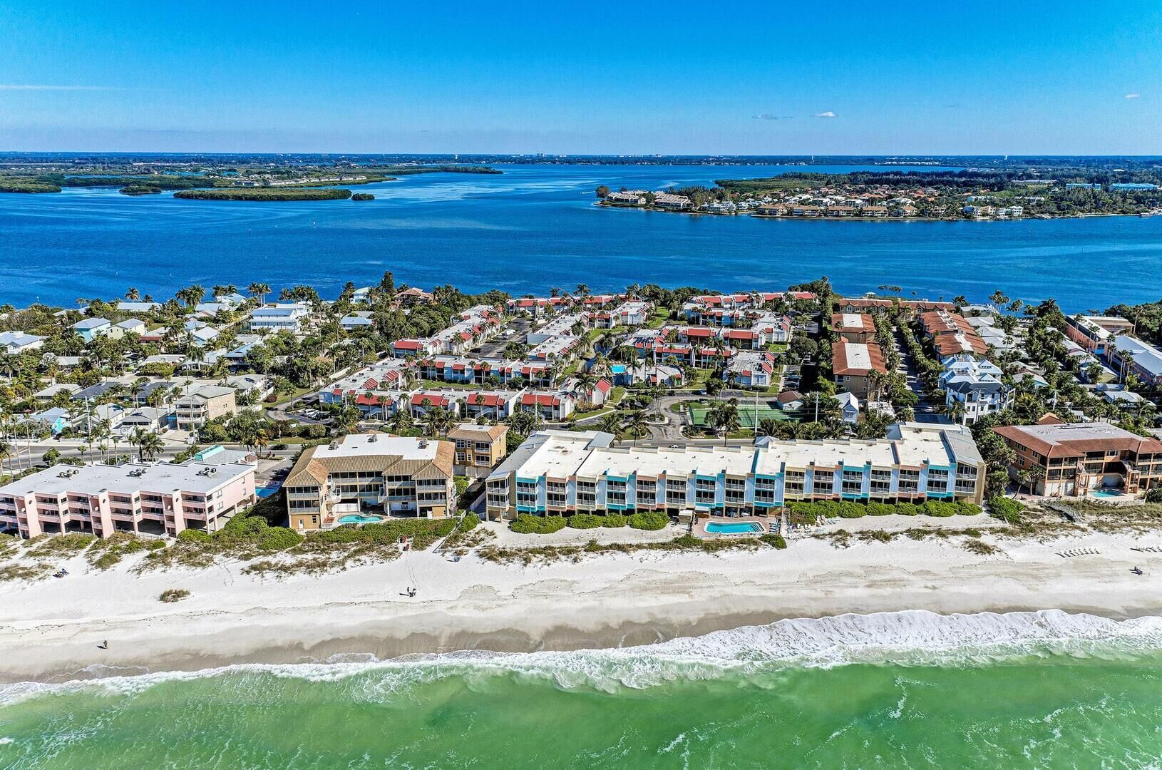 Een kustresort met strandwoningen, een jachthaven en een helder uitzicht op de oceaan.