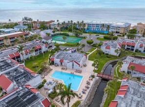 A resort with multiple buildings, a central swimming pool, and a view of the ocean.