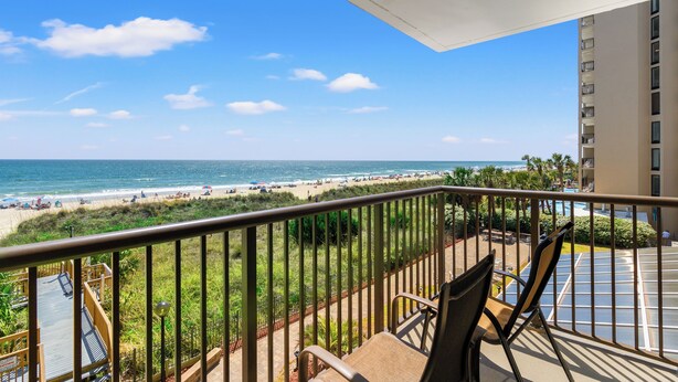 A balcony with a view of the beach and ocean.