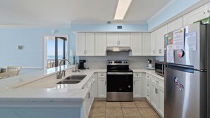 A kitchen with white cabinets, stainless steel appliances, and a view to the outside.