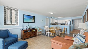 A living room with a blue sofa, a wooden cabinet, and a dining area with a table and chairs.