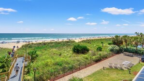 A beach view with a pathway leading to a seating area.