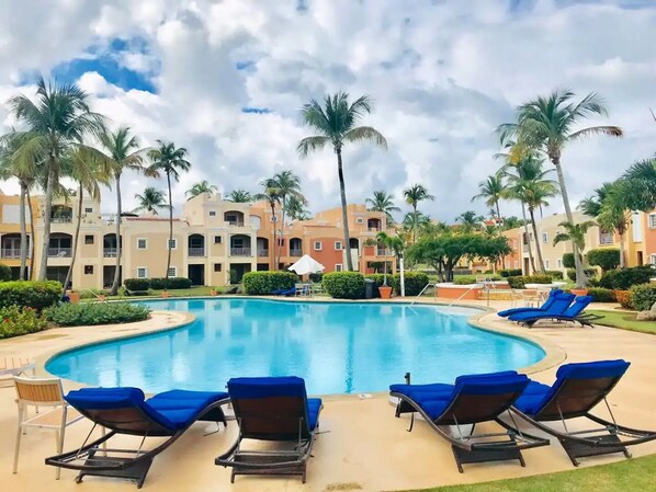 A pool area with lounge chairs, palm trees, and a building with balconies in the background. - SeaCret Suite @ Palmas del Mar - Humacao
(Humacao)