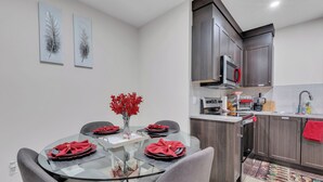 A modern kitchen with dark wood cabinets, a microwave, and a sink. - Beautiful Modern Unique Suite (Calgary)