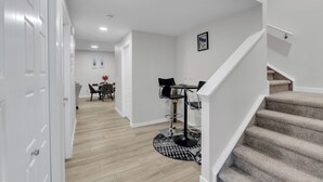 A modern interior with a staircase, a dining area with a round table and chairs, and a hallway leading to another room. - Beautiful Modern Unique Suite (Calgary)