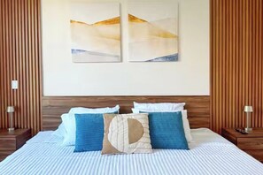 Habitación de hotel con una cama, dos cuadros colgados en la pared y paneles de madera.