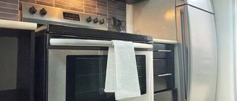 A kitchen with a stainless steel oven, a built-in microwave, and a refrigerator.